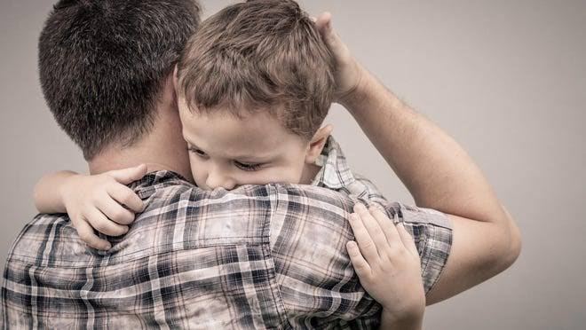父親擁抱孩子 · a father holding his child, the child's face against his shoulder