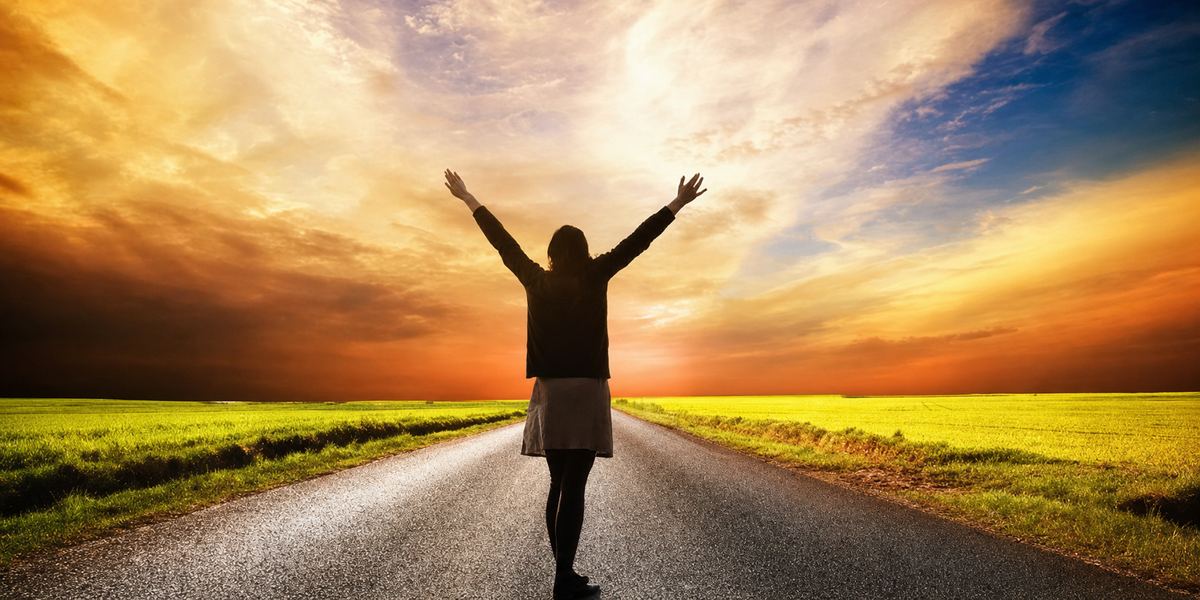 路中央張開雙臂的身影，背向落日 · a figure on an open road, arms raised against the sunset
